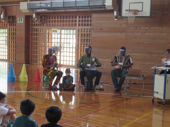 リベリア講座にて、民俗楽器の演奏を披露するスティーブンス・モール氏たち4名の写真。モール氏は向かって右端で小太鼓を演奏し、その左隣の奏者がジェンベを叩く様子が確認できる