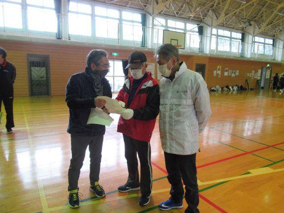 体育館館内にて、紙面に出力されたデータを見ながら参加者に助言を行うインストラクターの写真