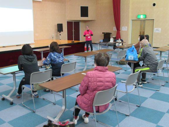 会議室にて、スライドショー形式によるインストラクターの講義を受ける参加者たちの写真