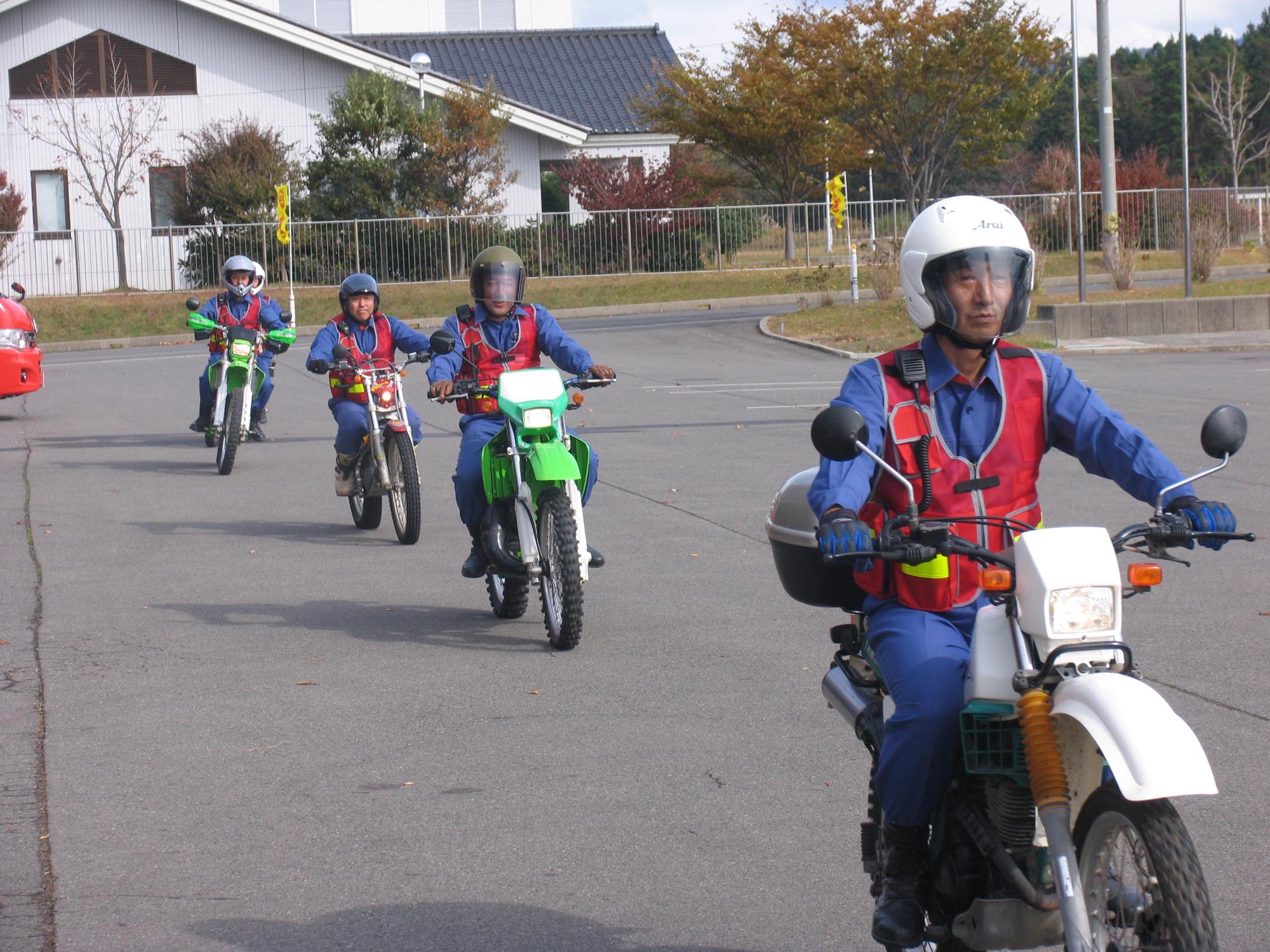 消防署内敷地を縦一列になってバイクで走行する4名の隊員たちの姿を撮影した写真