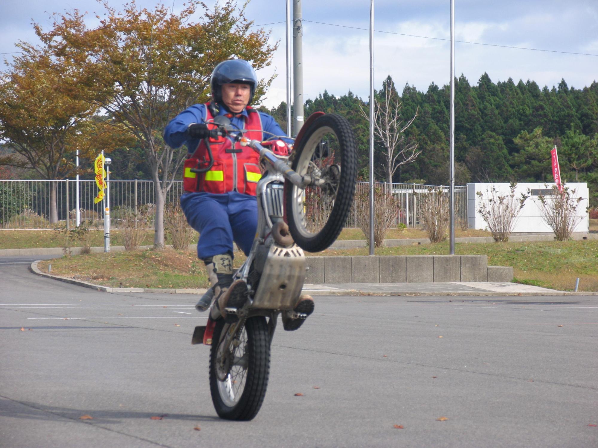 消防署敷地内にてバイク走行中にウィリーを披露する隊員を撮影した写真