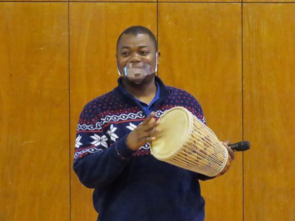 リベリア講座にて、アフリカの小太鼓を叩いてみせるスティーブンス・モール氏の写真
