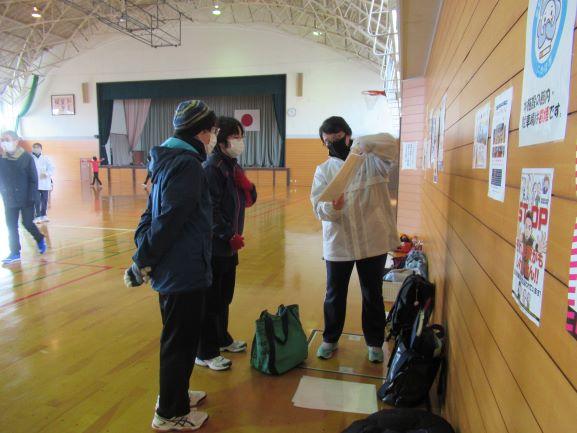 金浦体育館館内の壁際で、紙面に出力されたデータをもとにインストラクターの助言を聞く参加者たちの写真