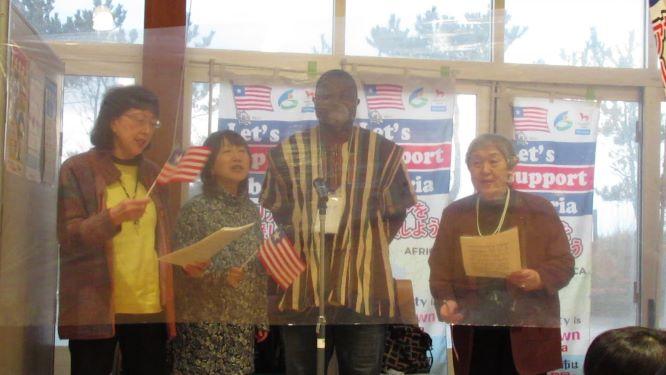 オンライントークにて、ミニサイズのリベリア国旗を持ちながらリベリア国歌を斉唱するスティーブンス・モール氏ほか、3名の参加者たちの写真