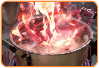 火にかかった厨房の鍋から大きな火が立ち昇っている写真